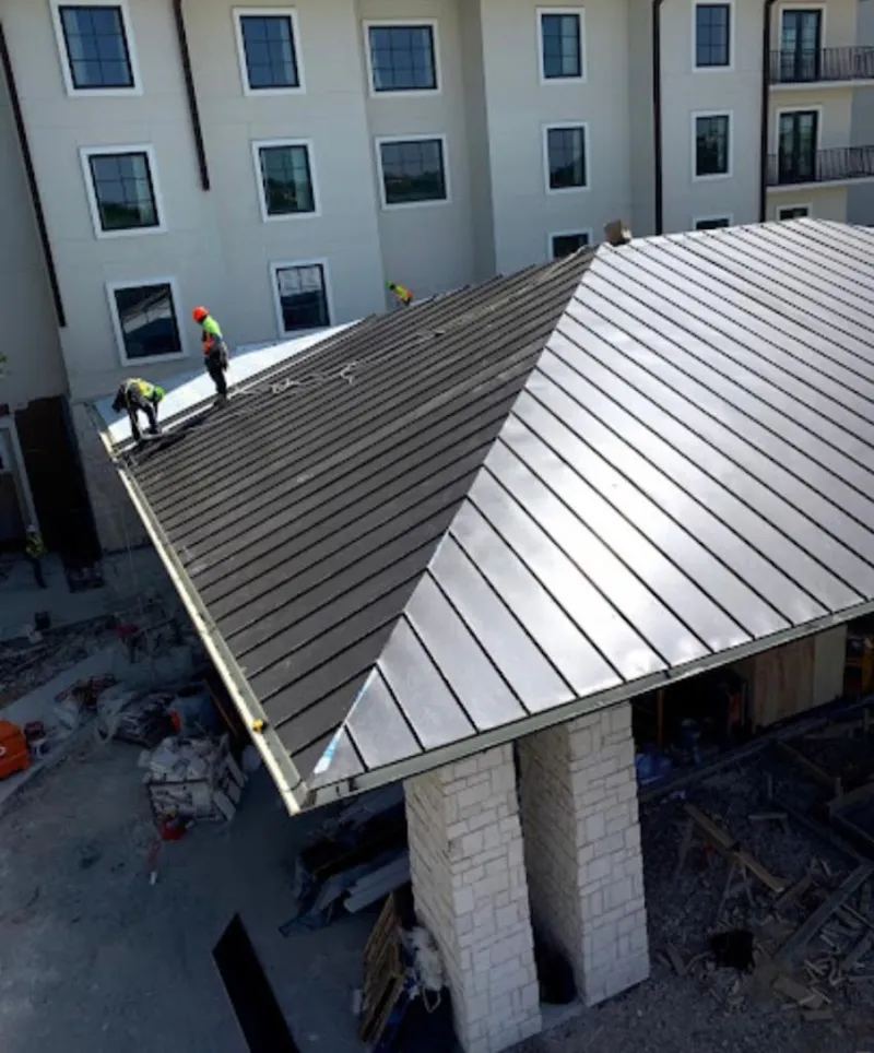 Crew installing standing seam metal roof panels on a commercial project in West Hartford